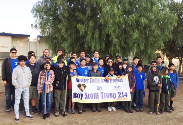 Photo of a group of several people, primarily boys, holding a banner that says Boy Scout Troop 214